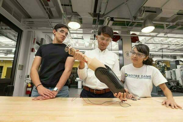 Two students with their professor examine prosthetic socket.